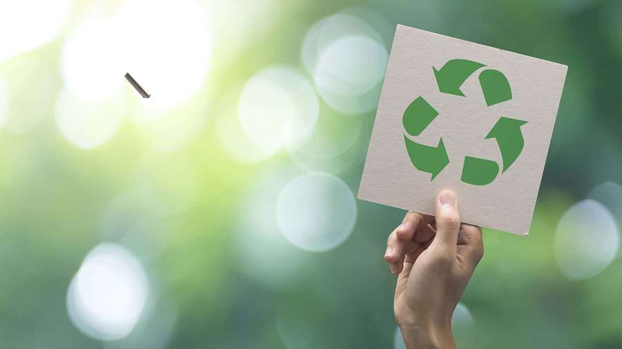 Mão segurando um cartão de símbolo de reciclagem em um ambiente verde natural. — Sustentabilidade Papéis de Parede