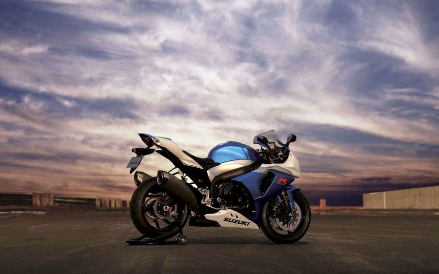 Blue and white Suzuki sport motorcycle on rooftop at dusk. — Suzuki Motorcycle Wallpaper