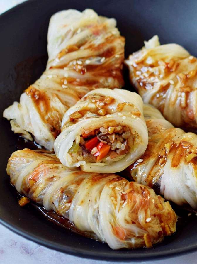 Kaalikääryleet värikkäällä täytteellä ja seesaminsiemenillä mustassa kulhossa. — Szechuan-kastike Taustakuvat