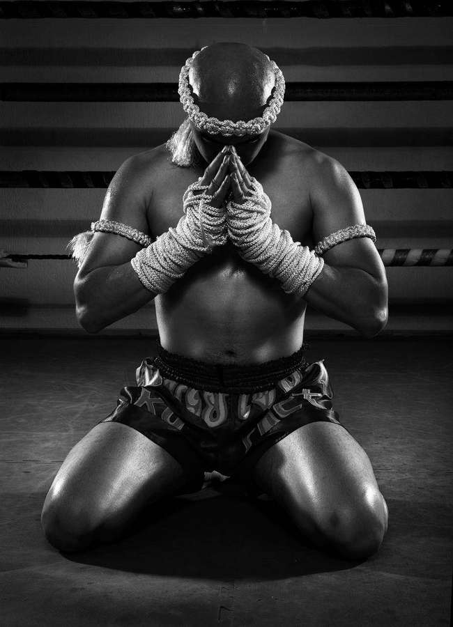 Lutador de Muay Thai ajoelhado em oração dentro de um ringue de boxe. — Tailândia Papéis de Parede