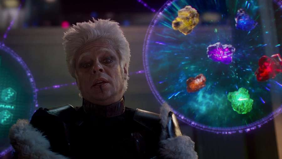 A man with white hair and dark makeup looks at floating glowing crystals in a sci-fi setting. — The Collector Wallpaper