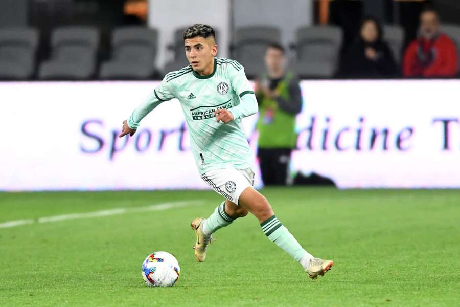 Soccer player dribbling ball on green field at night stadium — Thiago Almada Wallpaper