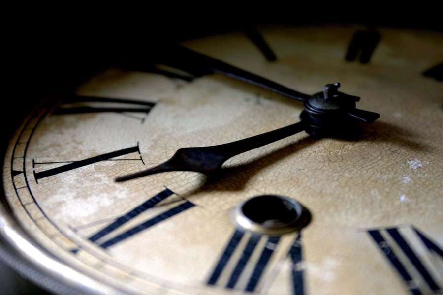 Close-up of a vintage clock face with cracked paint and Roman numerals. — Time Background