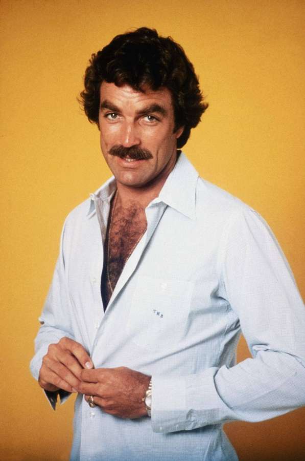 Man with mustache buttoning light blue shirt against yellow background — Tom selleck Background