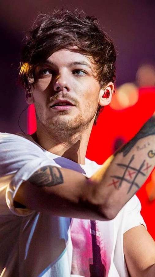 Male singer with tattoos performing on stage under red lights. — Tomlinson Wallpaper