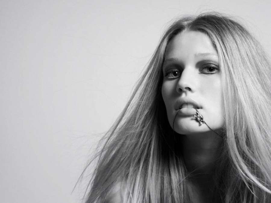 Woman with long hair and cross lip piercing in black and white studio portrait. — Toni Background