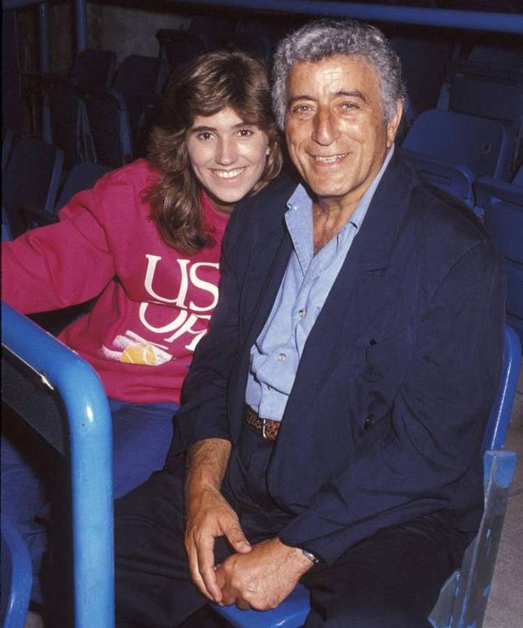 A man and woman smiling while seated in stadium bleachers. — Tony Bennett Background