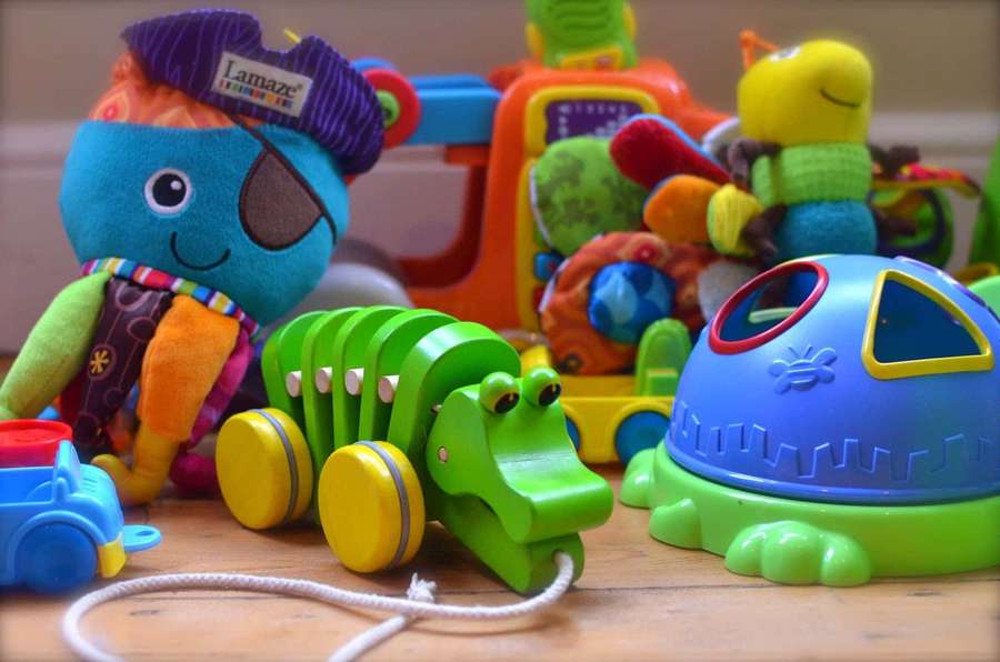 Brightly colored children's toys on a wooden floor including a plush pirate and a wooden alligator pull toy. — Toys Background