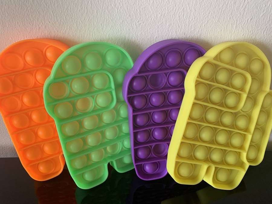 Four colorful silicone pop-it fidget toys leaning against a wall. — Toys Wallpaper