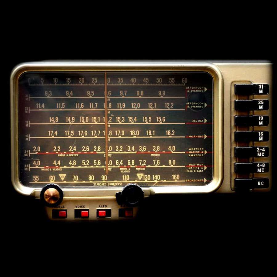 Primer plano de una radio vintage con diales de frecuencia iluminados y perillas. — Transmisión Fondos de pantalla