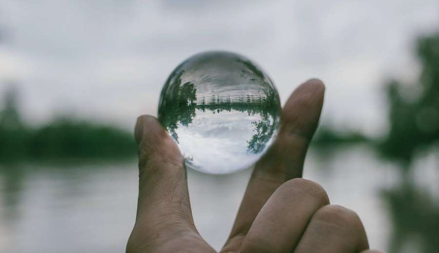Hand som håller en kristallkula som reflekterar en sjö och träd. — Transparent Bakgrundsbilder