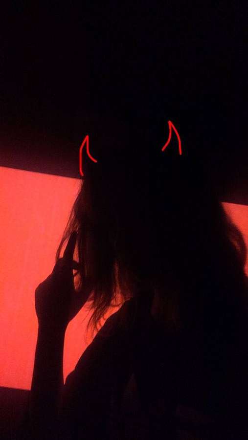 Person in Silhouette mit glühenden roten Teufelshörnern in einem dunkelrot beleuchteten Raum. — Trauriges Dämonenmädchen Bild Wallpaper