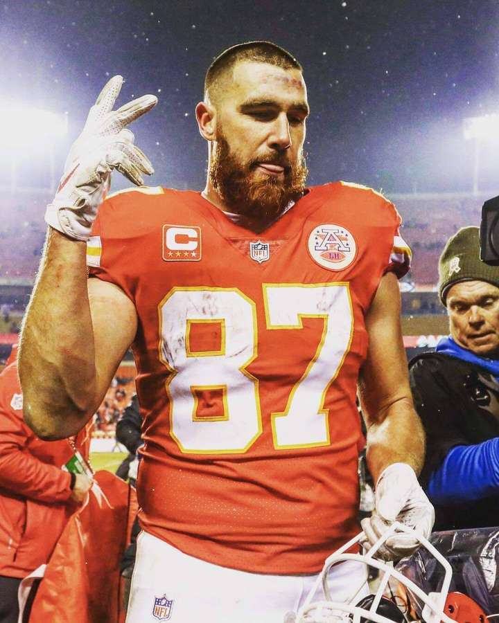 NFL-Spieler Nummer 87 in rotem Trikot gestikuliert auf dem Feld bei Nacht — Travis Kelce Wallpaper