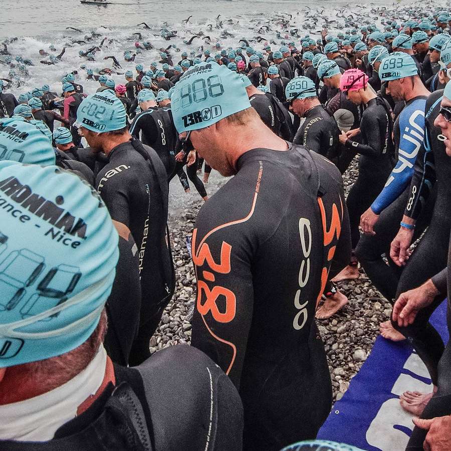 Triatletas con trajes de neopreno y gorros de natación preparándose para entrar al agua. — Triatlón Fondos de pantalla