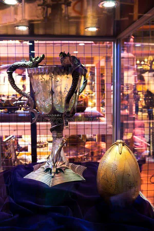 Hopeinen pokaali lohikäärmeen muotoisilla kahvoilla ja kultainen muna violetilla sametilla lasivitriinissä. — Triwizard Cup Taustakuvat