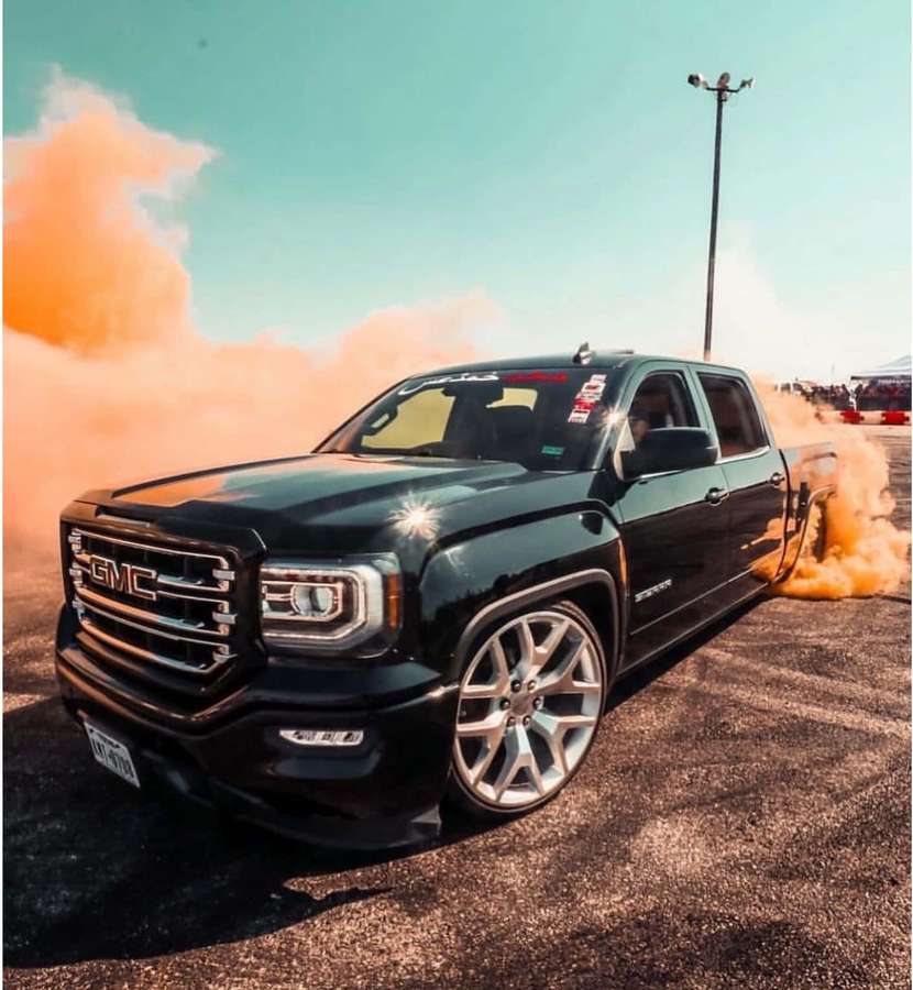 Black GMC truck burning rubber with orange smoke on asphalt at sunset. — Trokiando Wallpaper