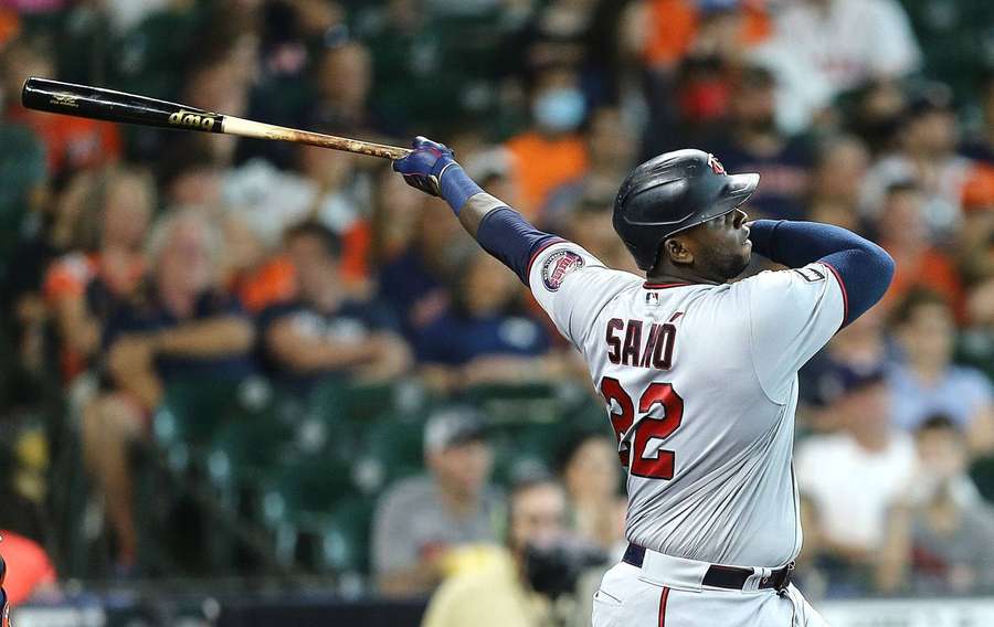 Baseball player swinging bat during night game with crowd behind. — Twins Background