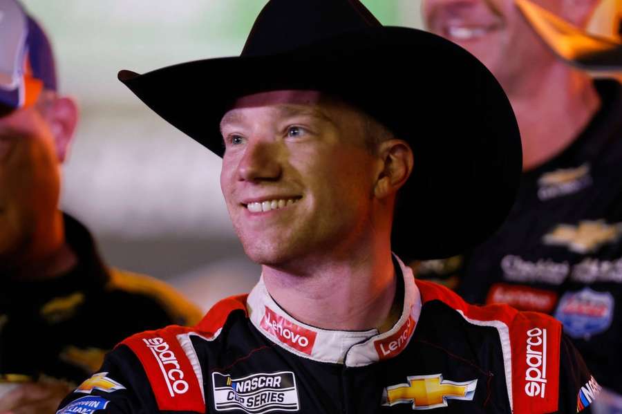 NASCAR driver wearing cowboy hat and racing gear smiling at event. — Tyler Reddick Wallpaper