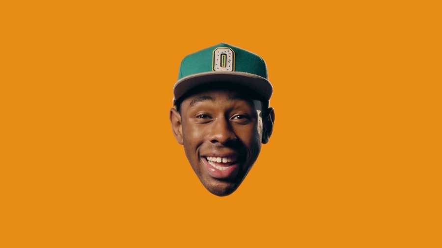 A smiling man wearing a green cap against an orange background. — Tyler The Creator Background