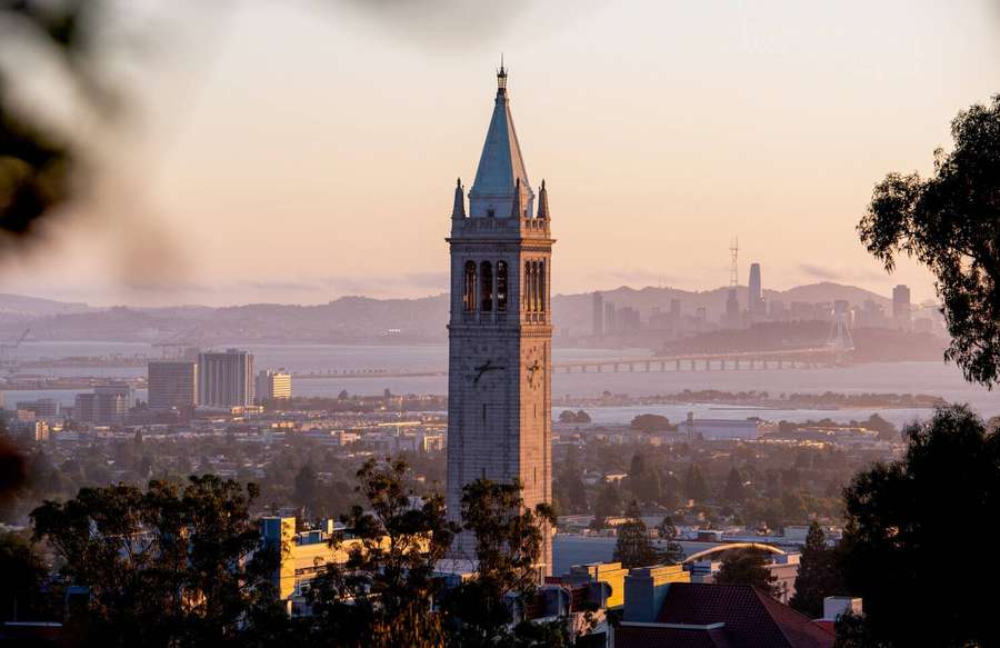 Clock tower at sunrise overlooking a city and bridge — Ucb Wallpaper