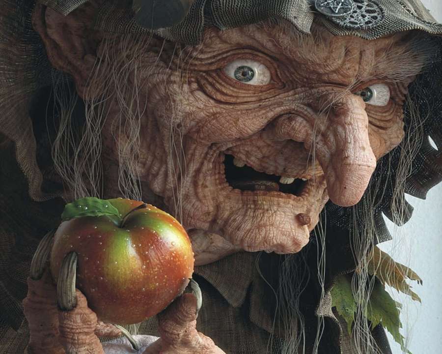 A scary witch with wrinkled skin holds a shiny red apple. — Ugly Background