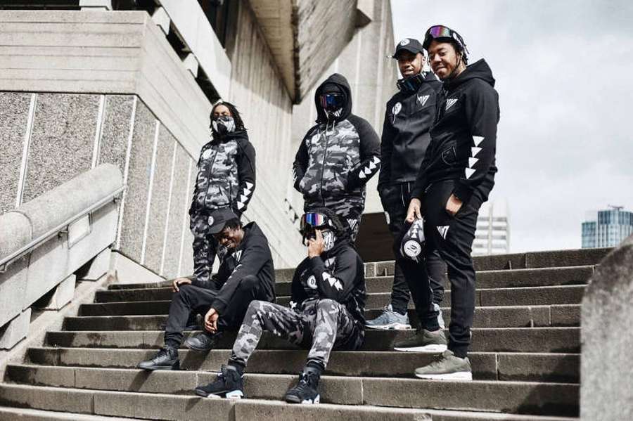 Five athletes in matching camouflage sportswear posing on concrete stairs in city. — UK Drill Background