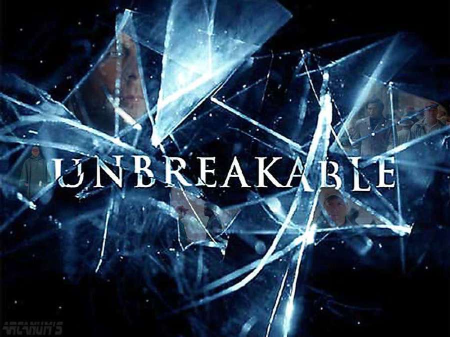 Shattered glass reveals ghostly faces behind the word 'UNBREAKABLE' in a dark scene. — Unbreakable Wallpaper