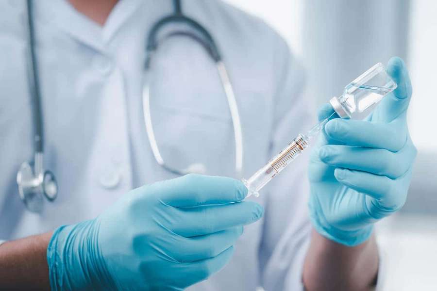 Doctor in blue gloves preparing a syringe with a vial and stethoscope. — Vaccine Wallpaper