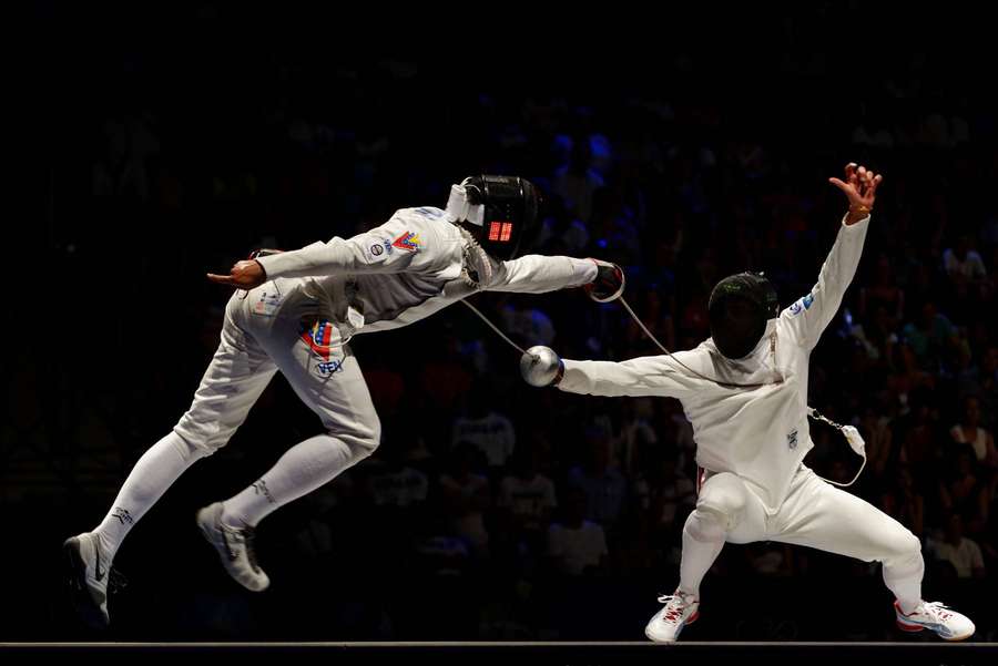 Dos esgrimistas con equipo blanco participan en un combate dinámico bajo las luces de la arena. — Vallas Fondos de pantalla