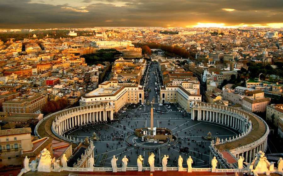 Praça de São Pedro na Cidade do Vaticano banhada pela luz dourada do pôr do sol com multidões e edifícios históricos. — Vaticano Papéis de Parede