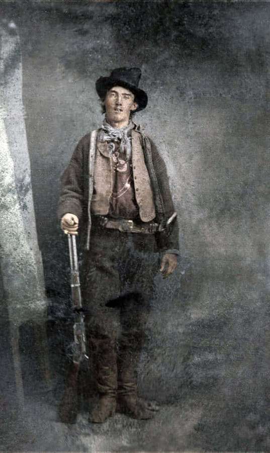 Giovane cowboy con cappello e gilet che tiene un fucile in un ritratto da studio. — Vecchie foto western Immagine