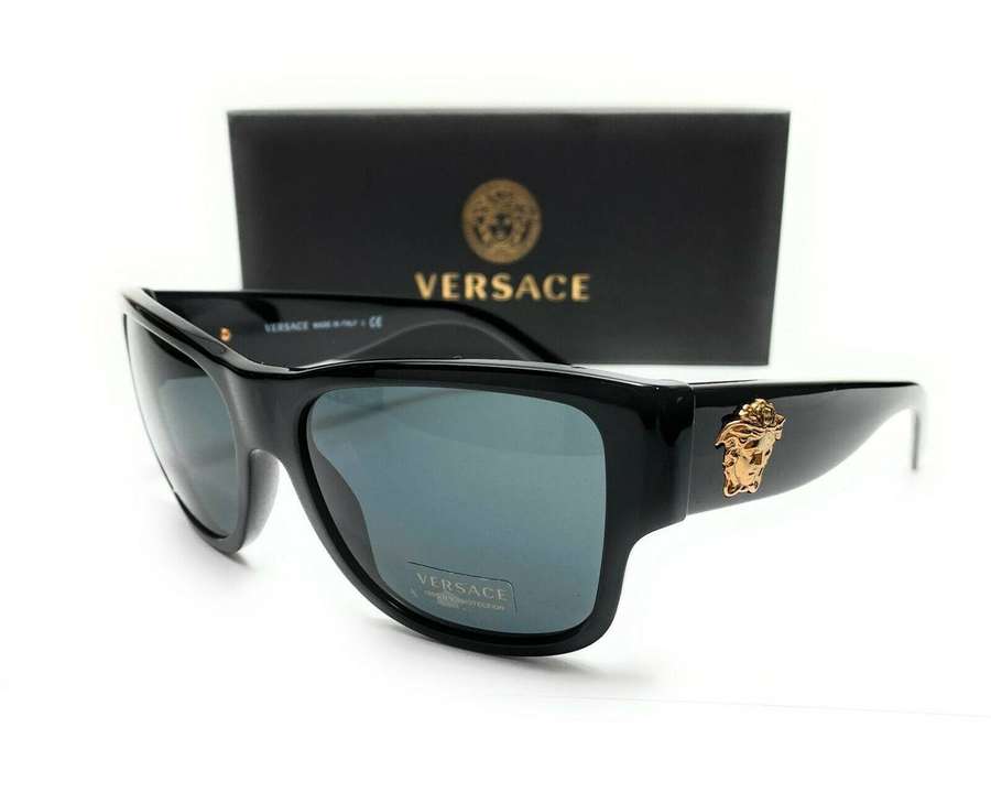 Occhiali da sole Versace neri con logo Medusa dorato e custodia marchiata su sfondo bianco. — Versace Sfondi