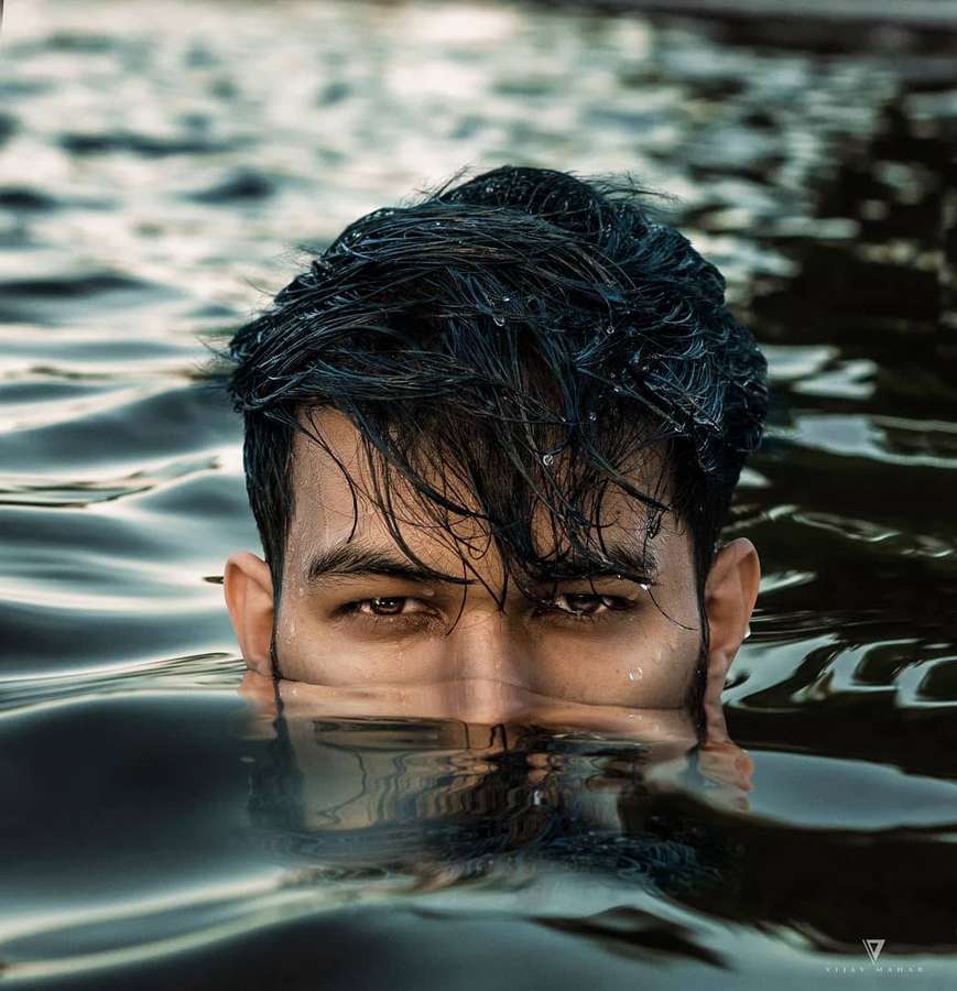 Man with wet hair emerging from water staring intensely at viewer — Vijay Mahar Background