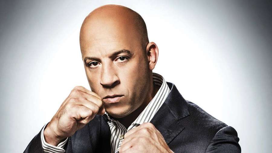 Actor Vin Diesel in a suit with fists raised looking intense. — Vin Diesel Wallpaper