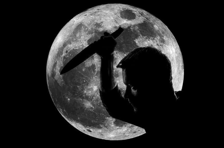 Person holding knife in front of full moon silhouette — Vindictive Wallpaper