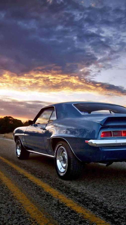 Blue classic muscle car driving on road at sunset. — Vintage Car iPhone Wallpaper