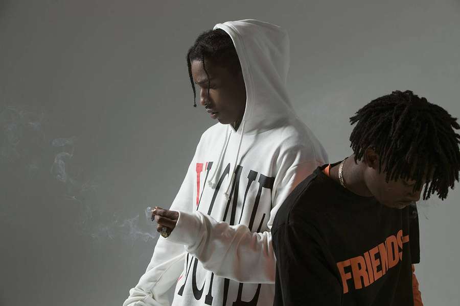 Two young men in hoodies one smoking the other looking down in a studio — Vlone Background