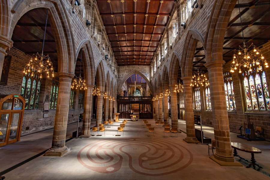 A cathedral with stone arches stained glass windows and a labyrinth floor lit by chandeliers. — Wakefield United Kingdom Wallpaper