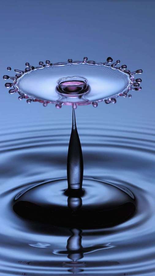 A water droplet suspended above a rippling surface creating a crown of splashes and concentric rings. — Water iPhone Wallpaper