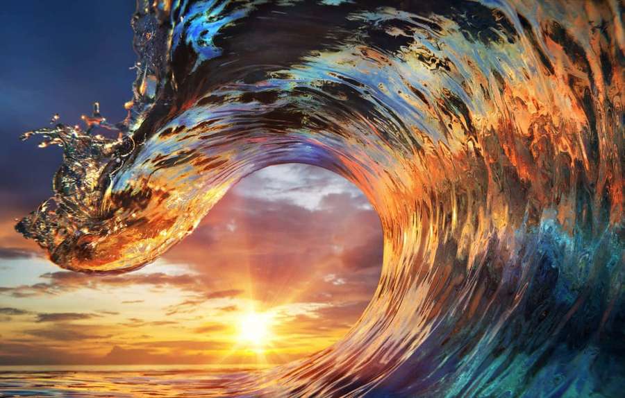 A massive curling wave frames a vibrant sunset over the ocean. — Waves Picture
