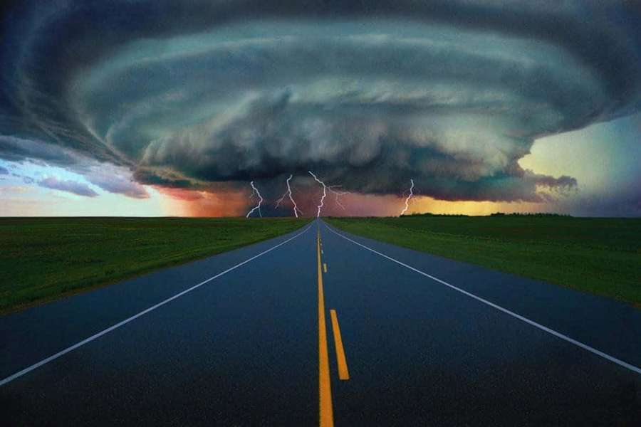A road leads into a storm with lightning and dark clouds at dusk. — Weather Background