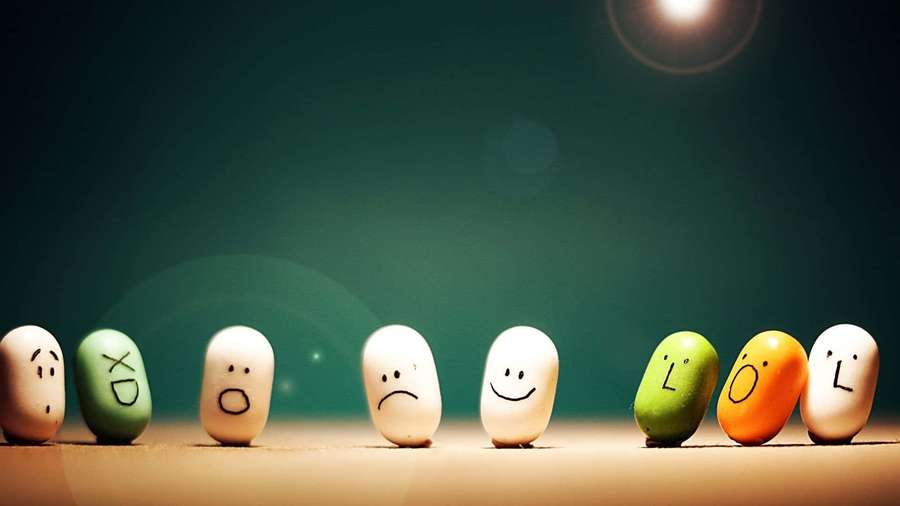 Line of beans with drawn faces and emoticons under spotlight. — Weird Background