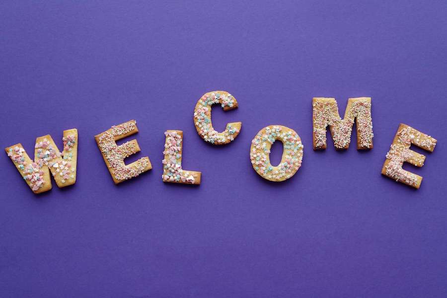 Cookies shaped like letters spelling welcome with colorful sprinkles on purple background — Welcome Wallpaper
