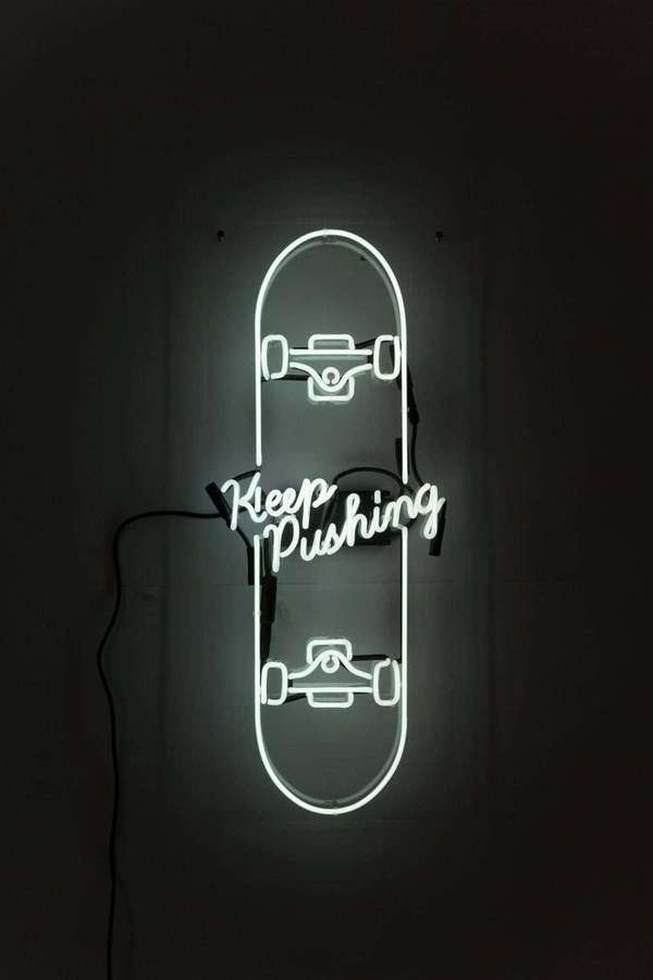 Neon sign shaped like a skateboard with the phrase 'Keep Pushing' glowing in a dark room. — White Neon Background