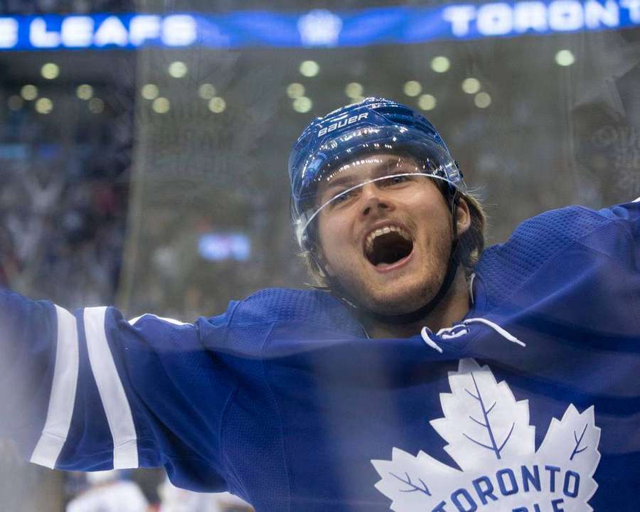 Hockey player in Toronto Maple Leafs jersey celebrating victory at rink. — William Nylander Background