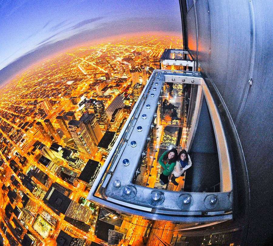 Kaksi ihmistä lasiparvekkeella katsellen hehkuvaa kaupunkia hämärässä. — Willis Tower Taustakuvat