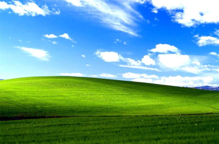 Welliger grüner Hügel unter einem hellblauen Himmel mit weißen Wolken. — Windows 95 Bilder