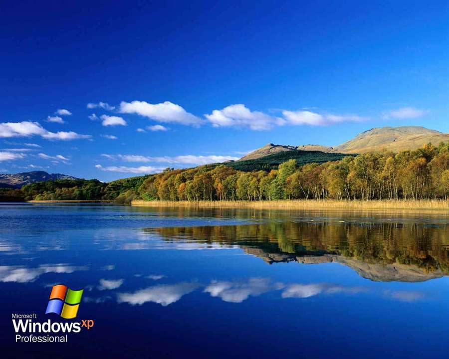 Lago autunnale che riflette foresta e cielo sotto cieli azzurri limpidi. — Windows Xp Logo Sfondi
