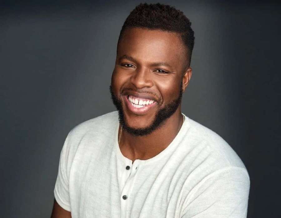 A smiling black man with a beard wearing a gray henley shirt. — Winston Duke Wallpaper