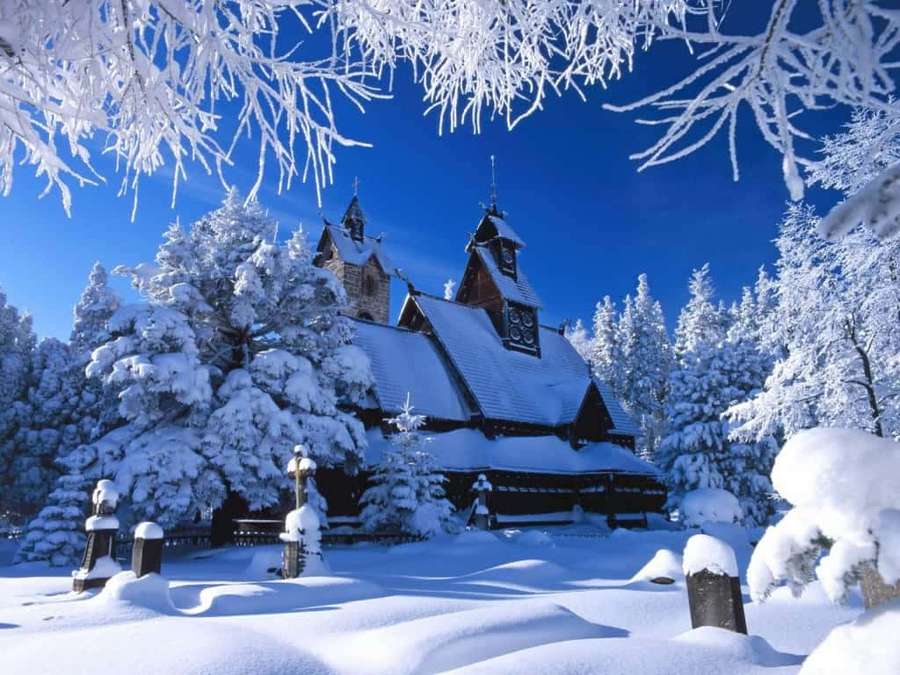 Snowy wooden church surrounded by frosted trees under a clear blue sky. — Winter Christmas Background